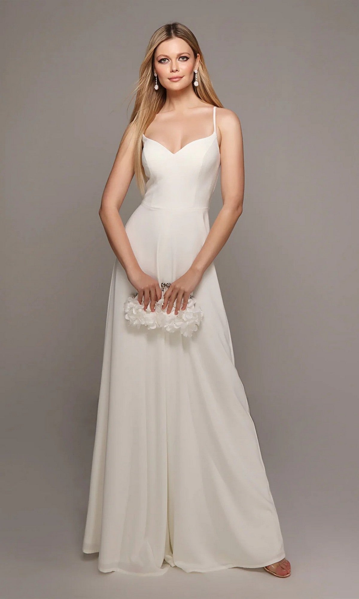 A woman in the Alyce 70022 long white jumpsuit with a sweetheart neckline holds a white floral clutch against a plain gray background.